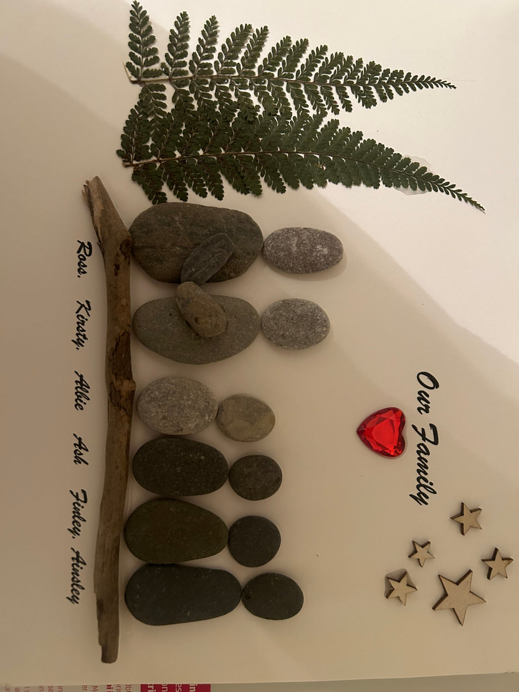 Personalised family pebble art with names on driftwood, pressed fern, red gem heart and wooden stars